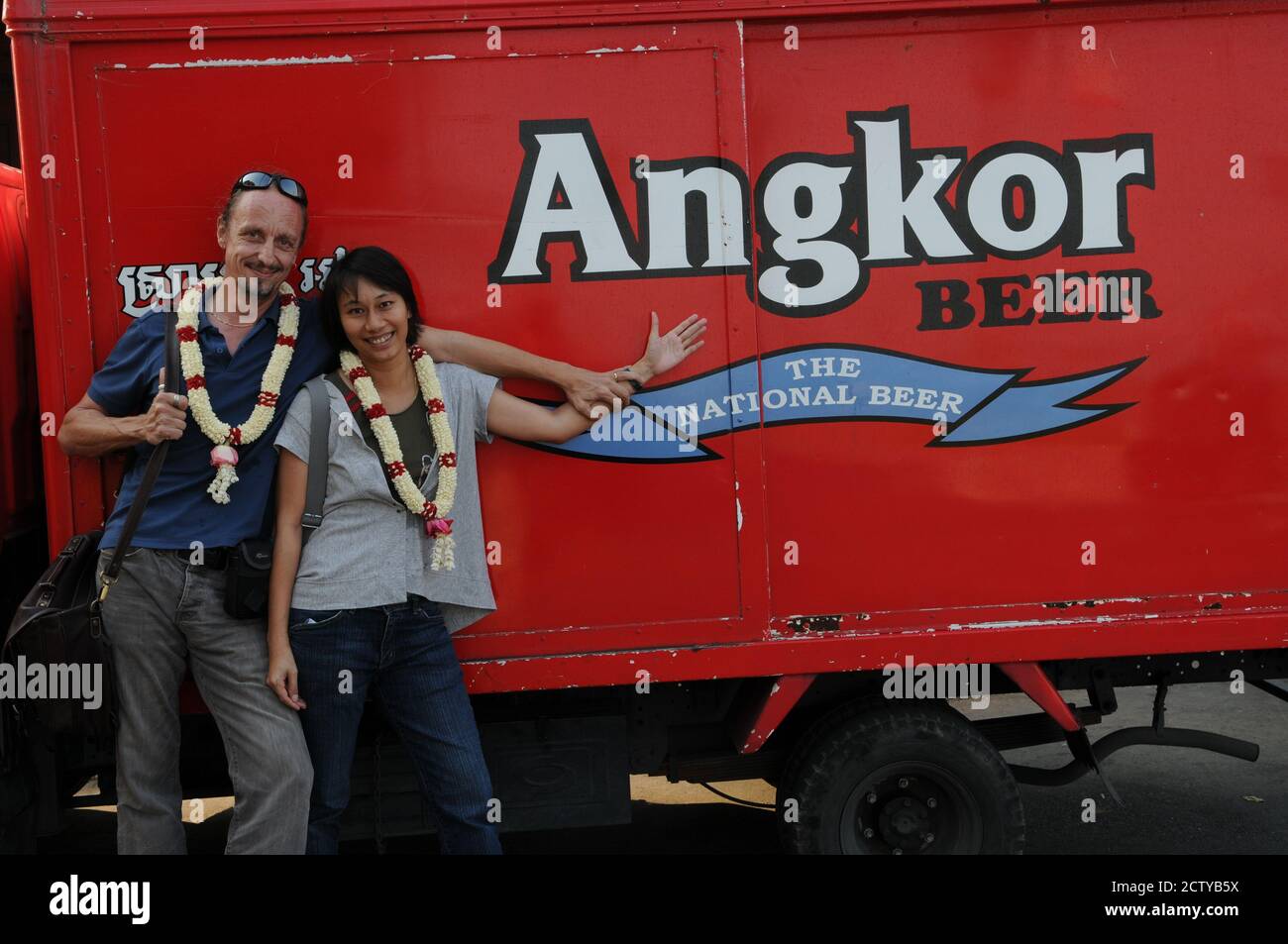 Il fotografo di avventura olandese Hans Kemp e la sua fidanzata tailandese, LAH, di fronte ad un camion della birra Angkor, indossando tradizionali wreaths cambogiani di benvenuto in gelsomino. Phnom Penh Cambogia. © Kraig Lieb Foto Stock