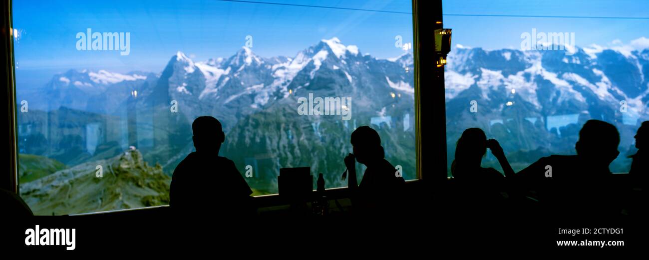 I turisti al ristorante Schilthorn 007 con Monte Eiger Mt Monch Mt Jungfrau sullo sfondo, Oberland Bernese, Svizzera Foto Stock