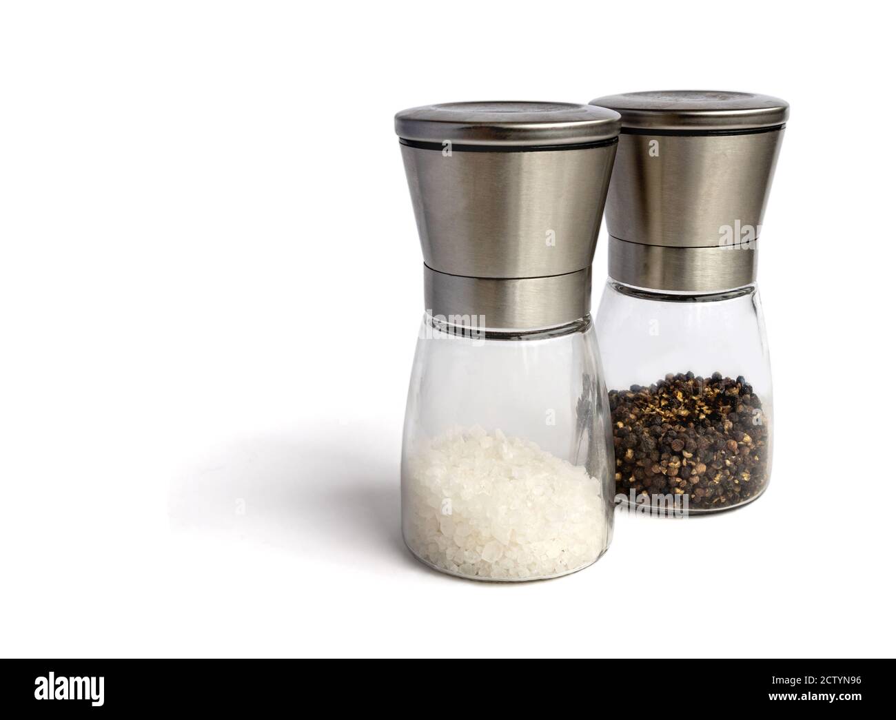 Set tritatutto per sale e pepe. Isolato su bianco. Smerigliatrici in vetro e acciaio inox. Ripieno di sale bianco macinato grossolano e pepe nero intero. Foto Stock