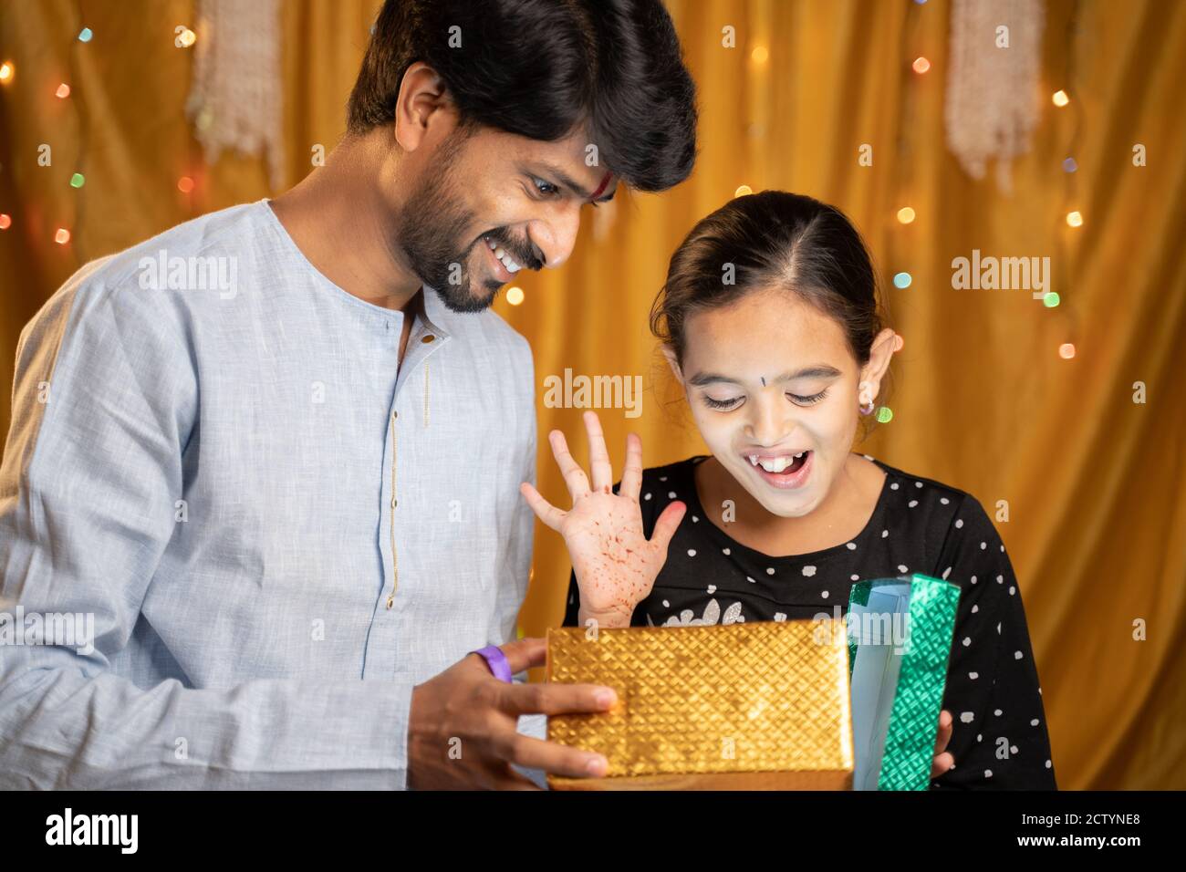 La piccola sorella eccitata ha ricevuto un regalo dalla sua seccatura durante la cerimonia del festival religioso indiano di Raksha Bandhan, Bhai Dooj o Bhaubeej Foto Stock