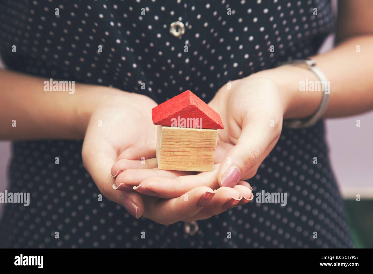 Donna che tiene una piccola casa nelle sue mani Foto Stock