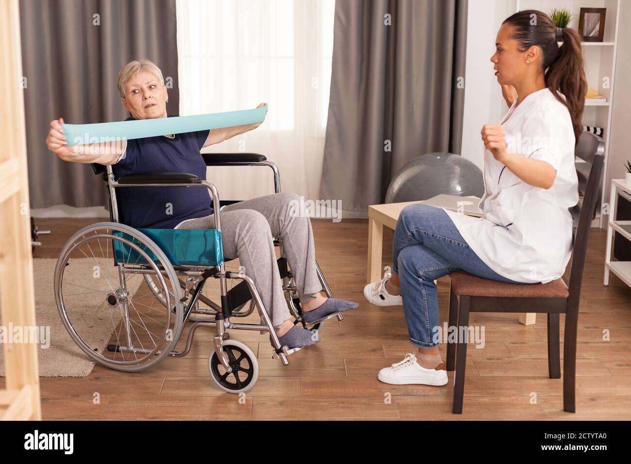Vecchia signora in sedia a rotelle con elastico. Disabile anziano ricoverato infermiera di aiuto professionale, cura di casa di riposo e riabilitazione Foto Stock