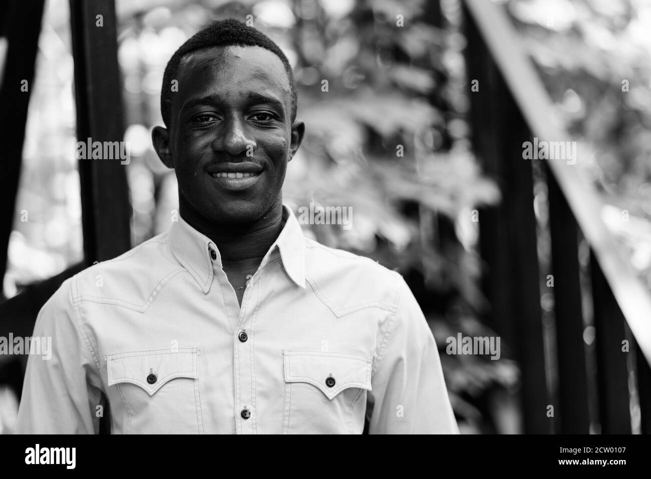 Giovani felici Africano nero uomo sorridente contro la moderna scala con la natura Foto Stock