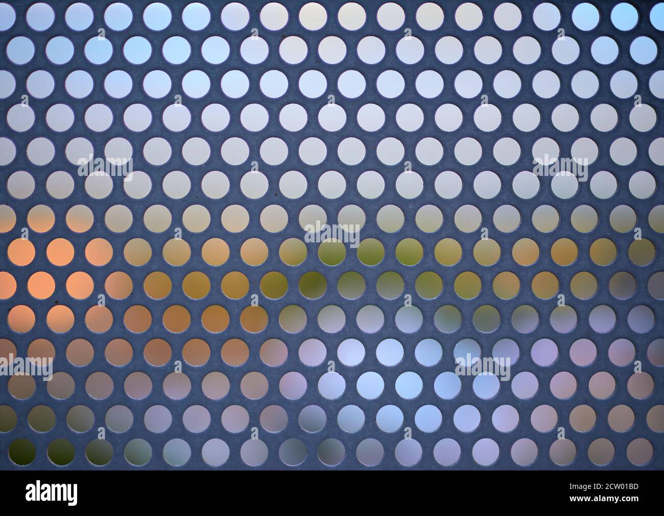 dettaglio di una lastra metallica forata in cui è possibile vedi il fondo del cielo e la vegetazione Foto Stock