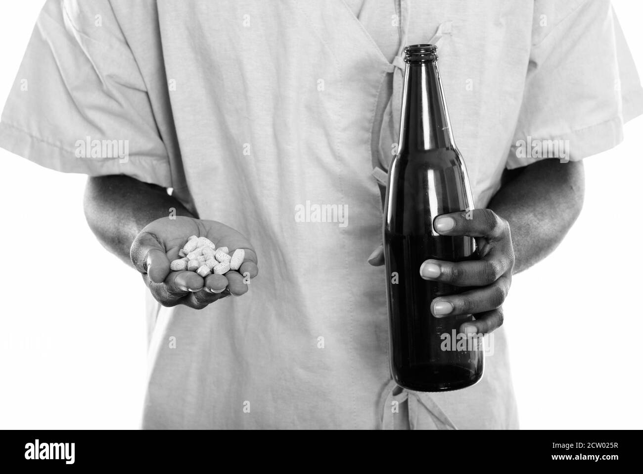 Studio shot delle mani del giovane africano nero uomo paziente tenendo la vitamina compresse e bottiglia di birra Foto Stock