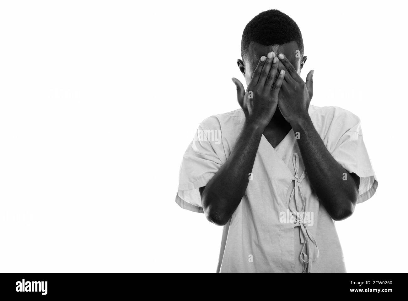 Studio shot del giovane africano nero uomo paziente che ricopre la faccia con entrambe le mani Foto Stock