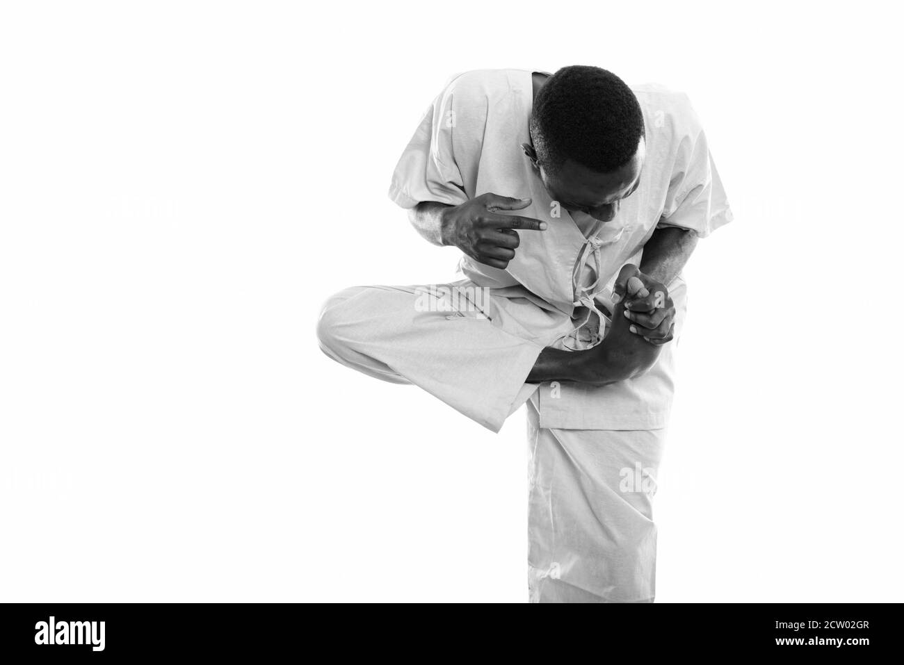 Studio shot del giovane africano nero uomo paziente in piedi mentre si tiene il piede dolente Foto Stock