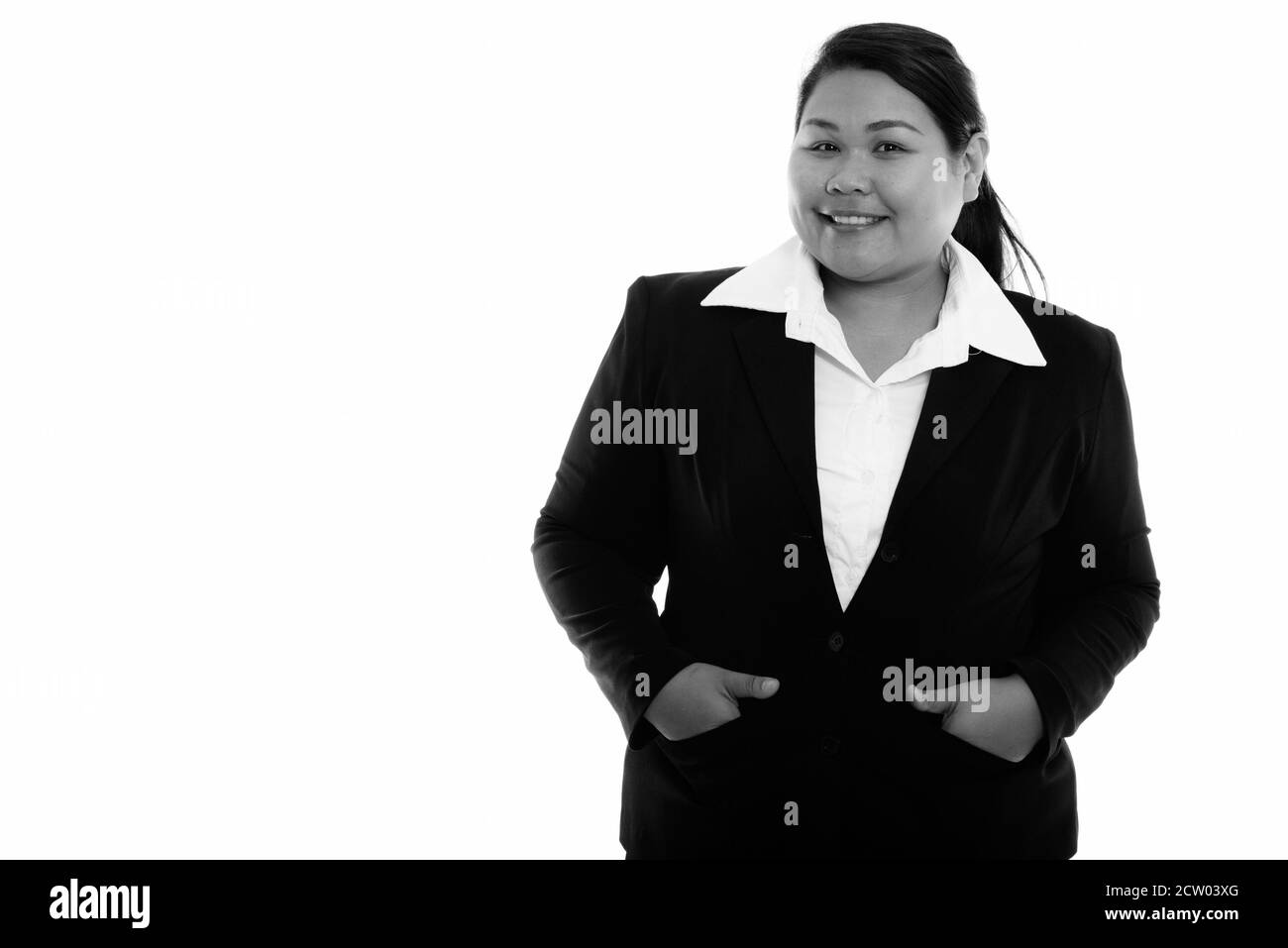Studio shot di giovani felici fat Asian imprenditrice sorridente con le mani sulle tasche Foto Stock