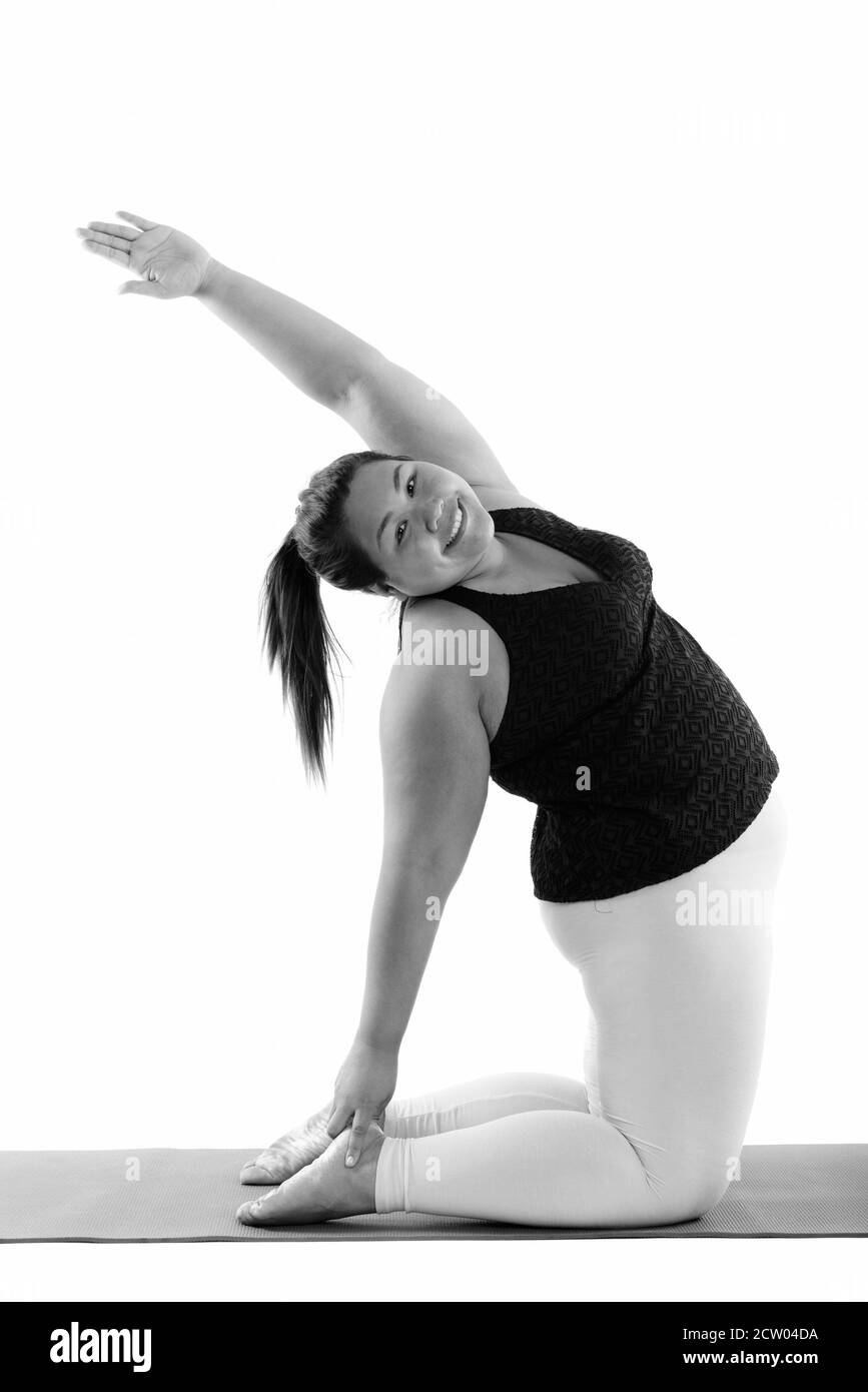 Studio shot di giovani felici fat donna asiatica sorridere mentre fare yoga pone Foto Stock