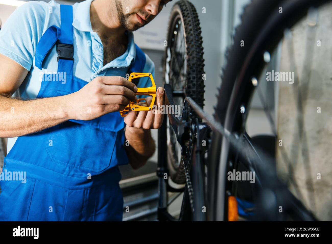 Riparazione della bicicletta in officina, l'operatore installa i pedali  Foto stock - Alamy