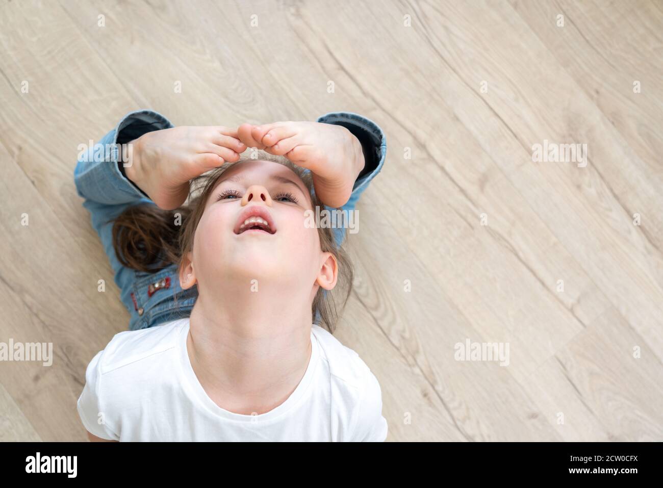 Bambina che pratica yoga a casa, stretching in raja bhudjangasana esercizio, re Cobra posa. Vista dall'alto Foto Stock