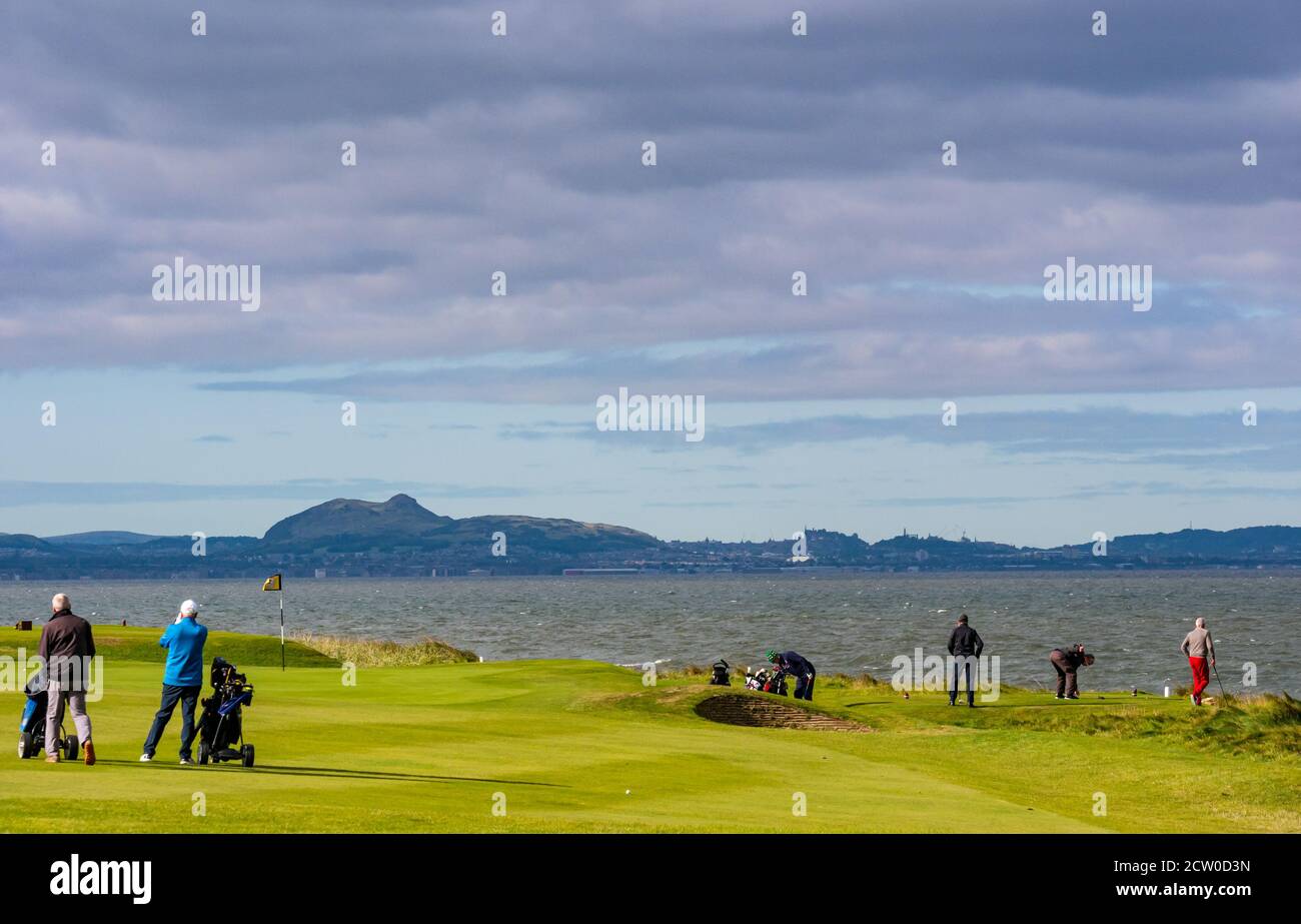 East Lothian, Scozia, Regno Unito, 26 settembre 2020. Regno Unito Meteo: I golfisti al campo da golf Craigielaw sono fuori in vigore sotto il sole nonostante il vento forte con una vista attraverso il Firth of Forth dello skyline di Edimburgo Foto Stock