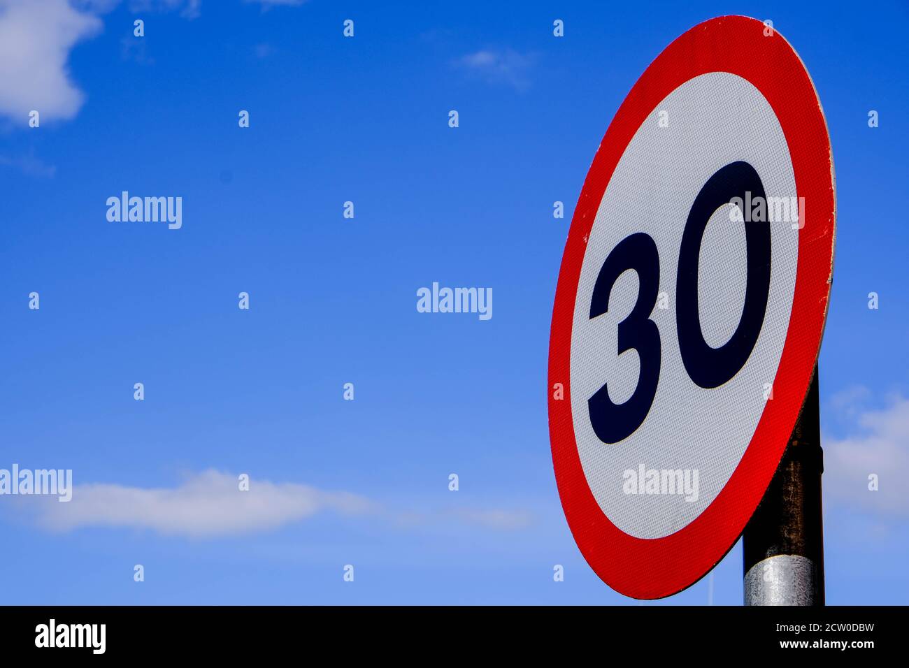 Segnale del limite di velocità di 30 mph per il traffico stradale, contro un cielo estivo blu Foto Stock