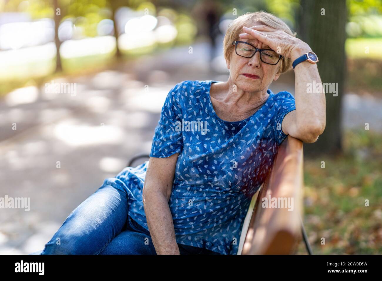 Donna anziana che soffre di mal di testa all'aperto in città Foto Stock