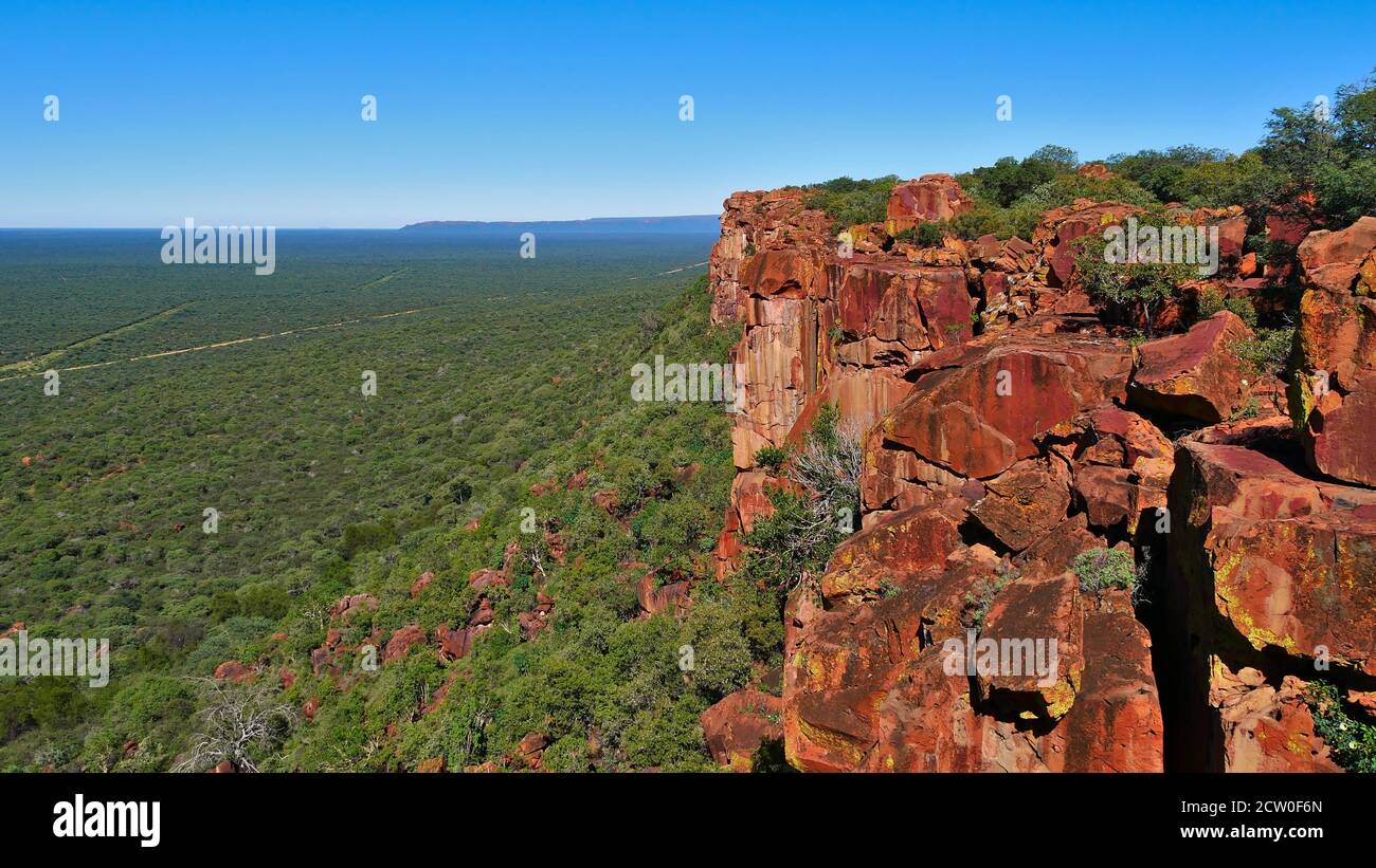 Vista panoramica sul deserto di Kalahari coperto da cespugli fuori all'orizzonte dal crinale di rocce di colore rosso dell'altopiano di Waterberg, Namibia, Africa. Foto Stock