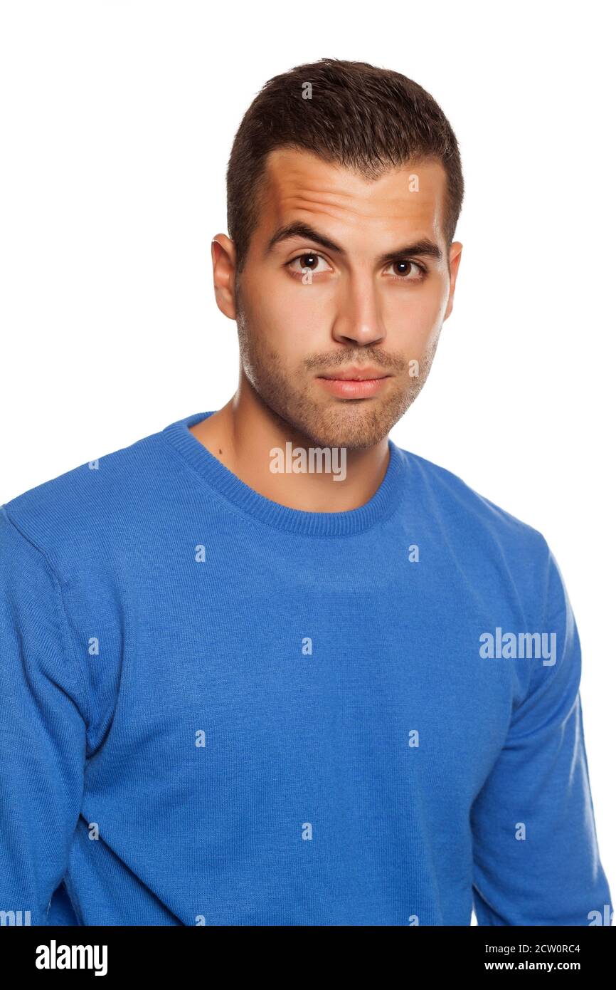 giovane uomo in blusa con uno sguardo scettico su sfondo bianco Foto Stock