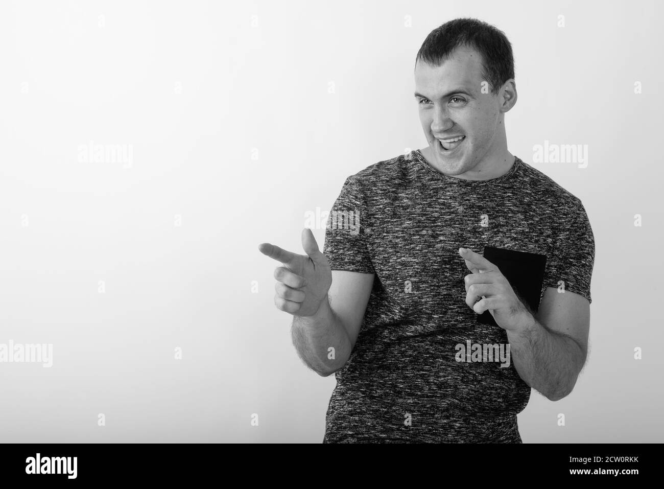 Studio shot di giovani felici muscolare di uomo sorridente mentre puntando entrambe le dita al lato contro uno sfondo bianco Foto Stock
