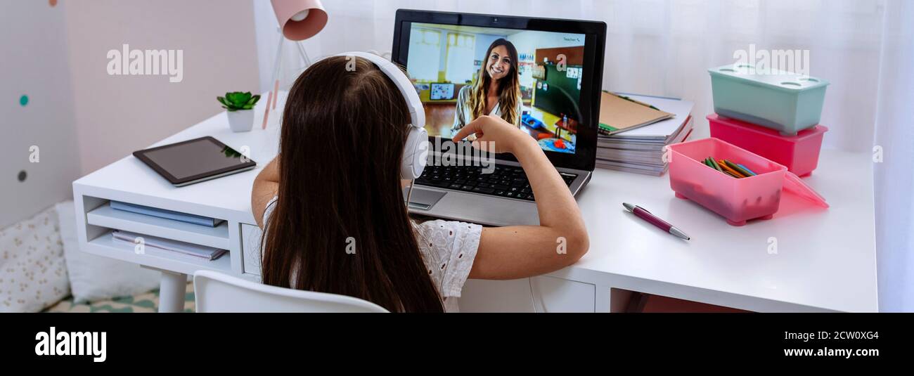 Ragazza a casa ricevendo classe online dal suo insegnante Foto Stock