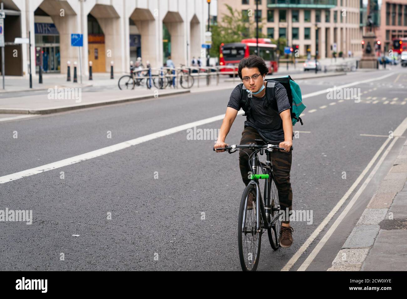 LONDRA, INGHILTERRA - 24 LUGLIO 2020: Ciclista dei corrieri di Deliveroo maschi asiatici giovani su una consegna di cibo a pranzo durante la pandemia di coronavirus COVID-19 - 1 Foto Stock