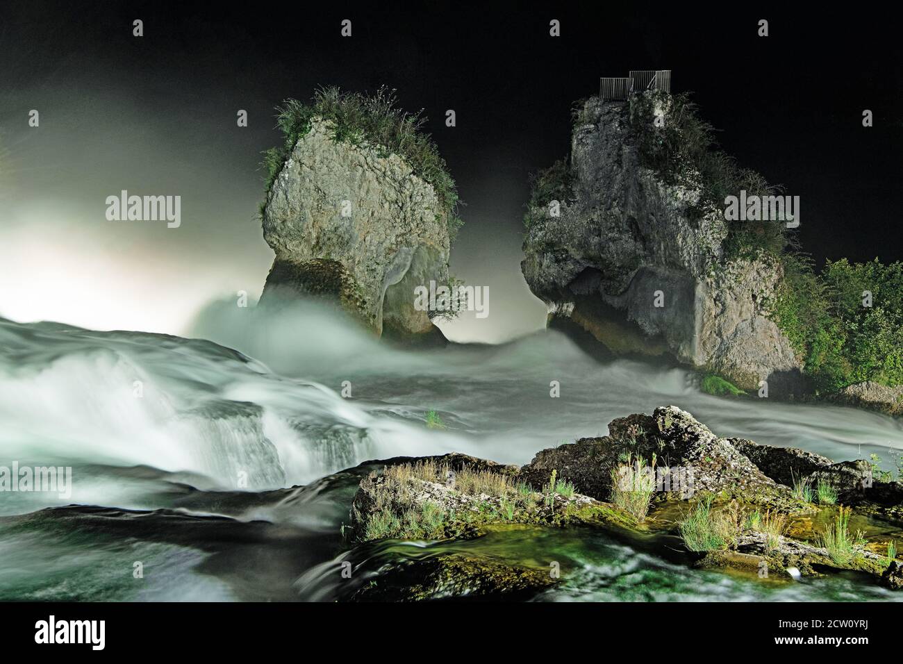 Rocce e vegetazione tra l'acqua corrente in serata Foto Stock