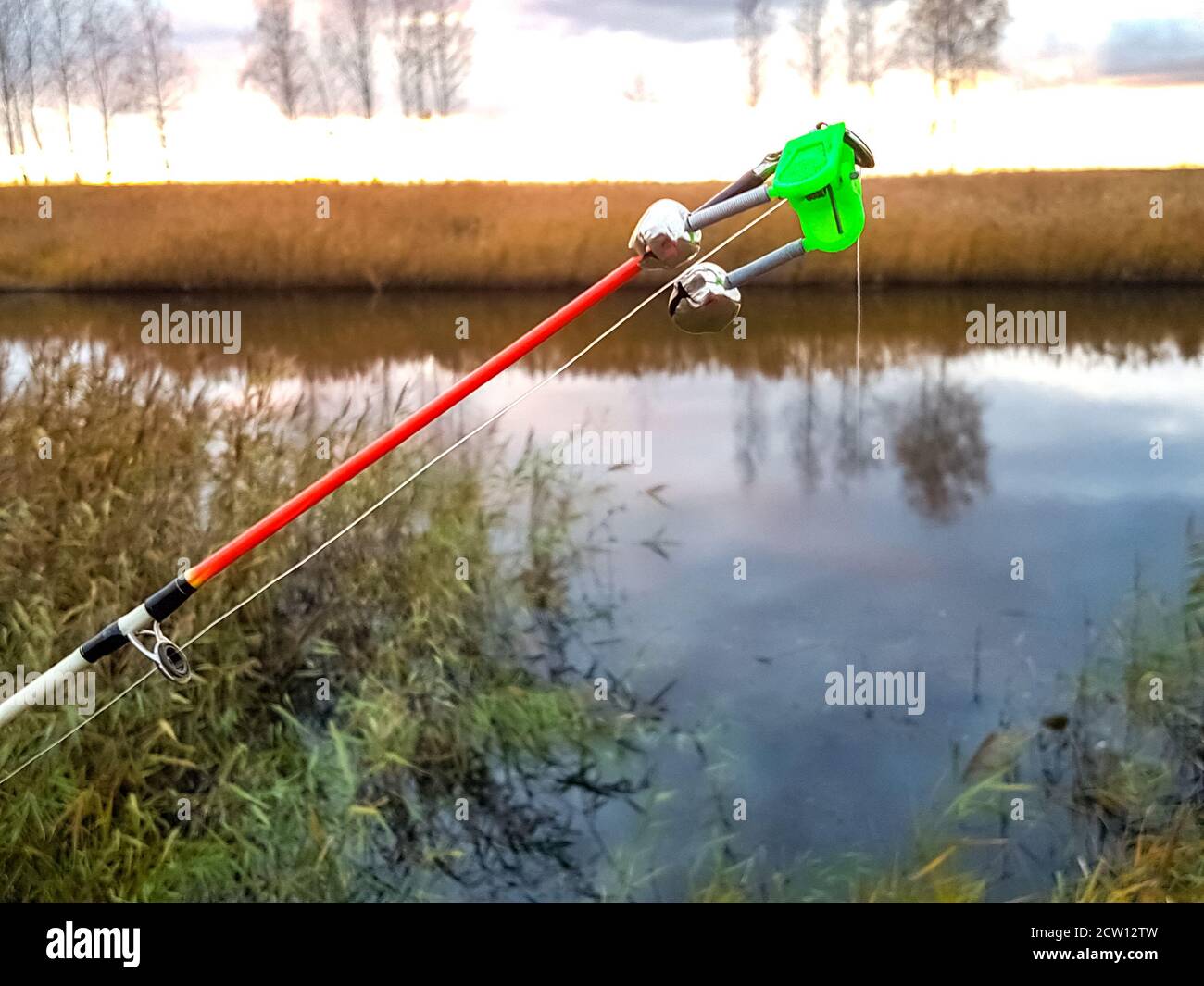 Paesaggio serale al fiume. Canna da pesca in erba autunnale. Foto Stock