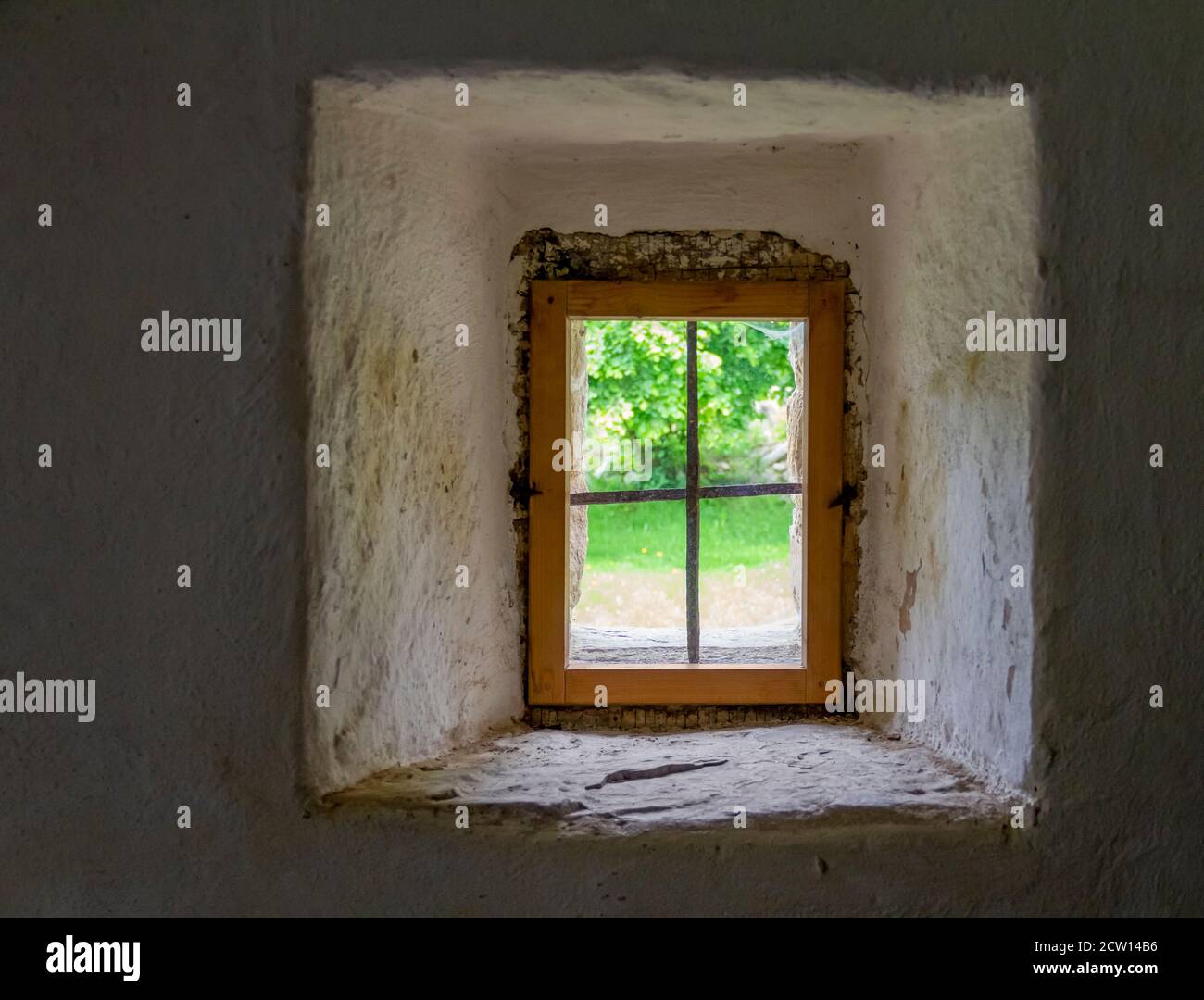 paesaggio soleggiato visto attraverso una finestra storica in un denso parete Foto Stock