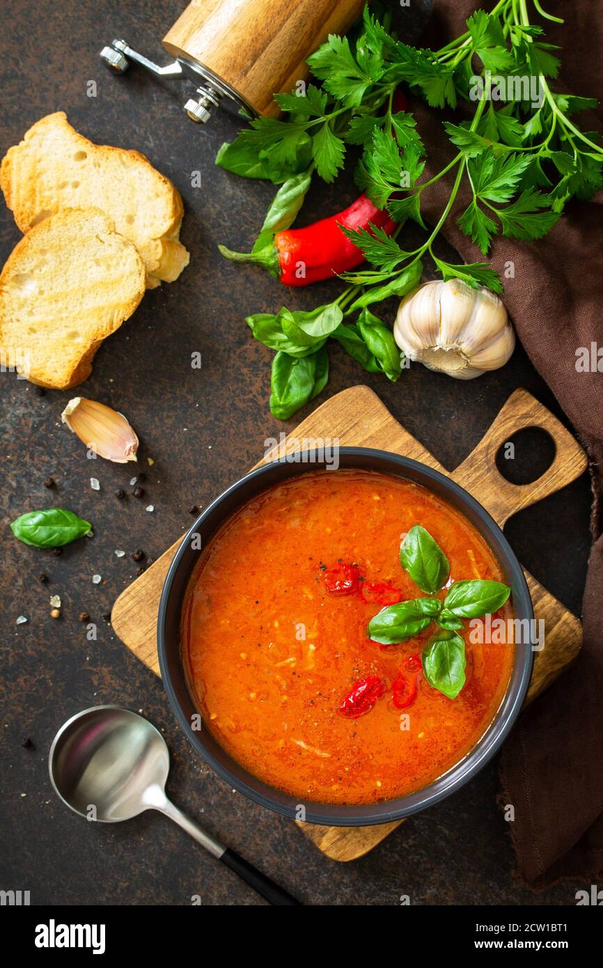 Cibo vegano sano. Zuppa di pomodoro o gazpacho su un tavolo di pietra scura o ardesia. Vista dall'alto in posizione piatta. Foto Stock