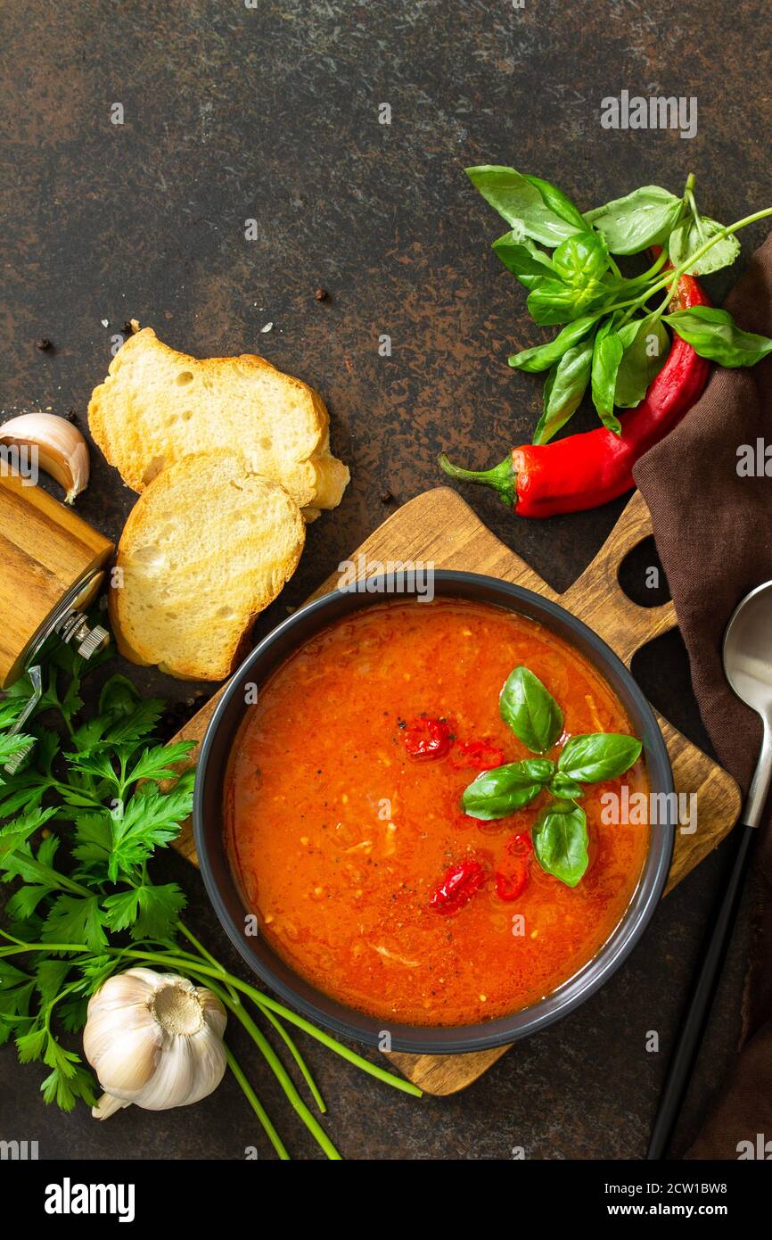 Cibo vegano sano. Zuppa di pomodoro o gazpacho su un tavolo di pietra scura o ardesia. Vista dall'alto in posizione piatta. Spazio di copia. Foto Stock