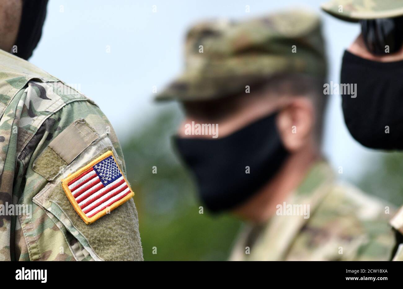 Bandiera americana sul braccio del soldato e sui soldati statunitensi che indossano maschere facciali di protezione. Quarantena in esercito. Forze militari degli Stati Uniti d'America. Foto Stock