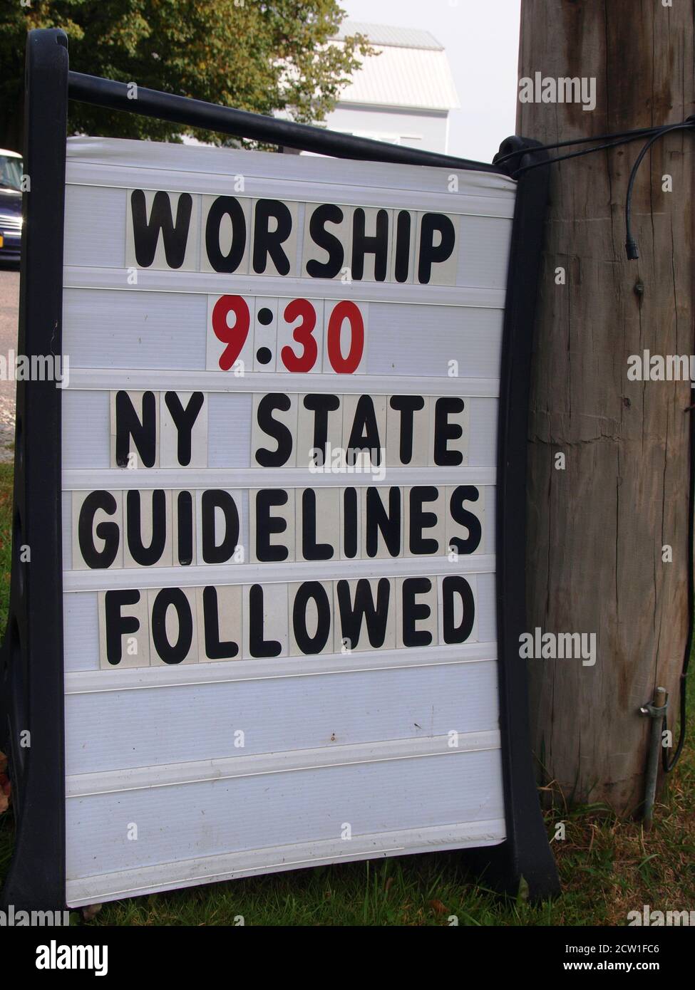 Il segno della Chiesa nell'era di Covid-19 dice 'il culto 9:30 Sono state seguite le linee guida dello Stato di NY' per la sicurezza dei parrocchiani e per limitare la diffusione della malattia Foto Stock