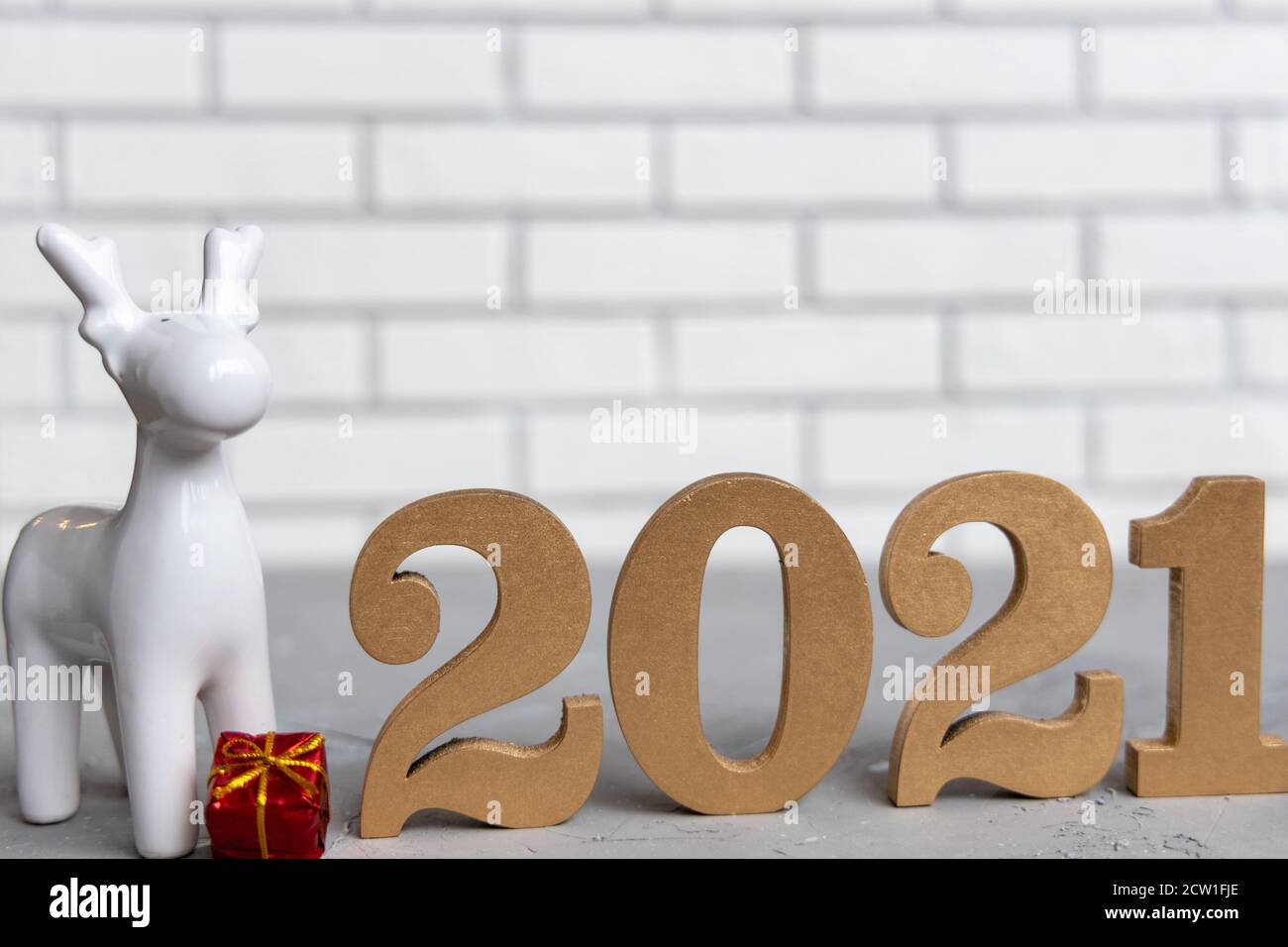 Fondo rosso di nuovo anno con numeri dorati lucenti 2021 e cono di pino argentato. Concetto minimalista su carta rossa con ombre dure. Foto Stock