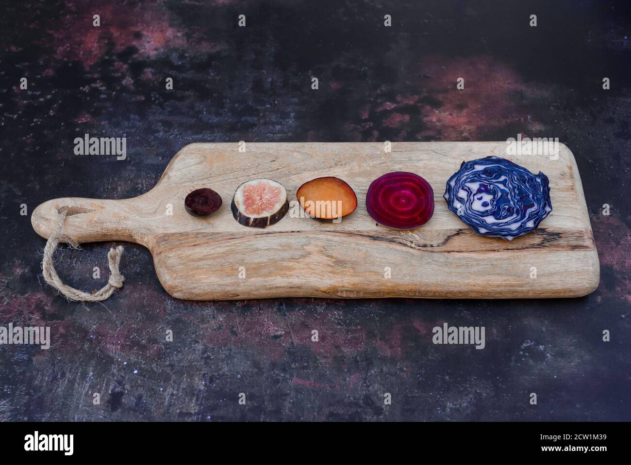 verdure tagliate a fette su un pannello di legno. Sfondo scuro Foto Stock