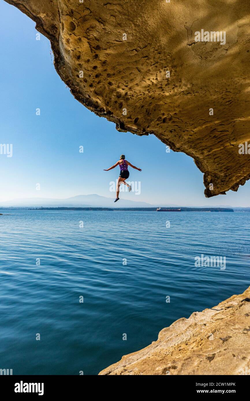 Un giovane ponticello della scogliera galleggia sospeso nell'aria prima di tuffarsi nell'oceano sull'isola di Gabriola, Columbia Britannica, Canada. Foto Stock