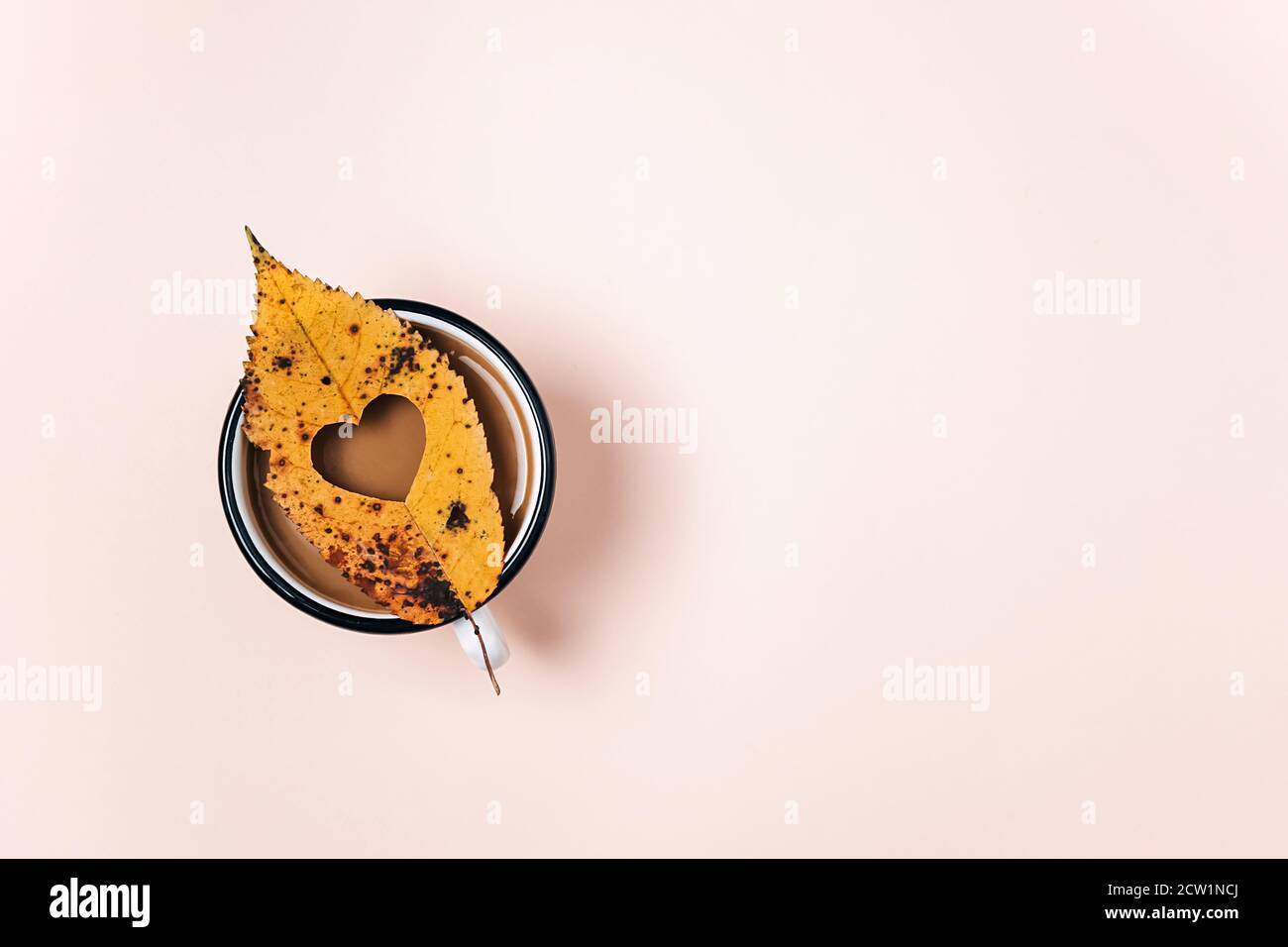 Cuore scolpito nel mezzo di una foglia secca e caffè caldo tazza su sfondo rosa per la pubblicità. Simbolo dell'amore, amanti dell'autunno. Ringraziamento, caduta, hal Foto Stock