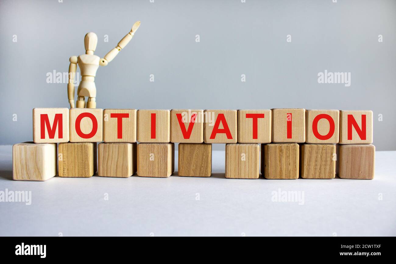 'Motivation' scritto su blocchi di legno. Concetto aziendale. Modello di legno di umano. Spazio di copia. Splendido sfondo bianco. Foto Stock