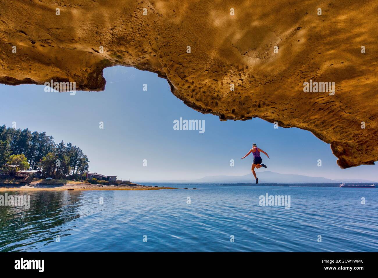 Un giovane ponticello della scogliera galleggia sospeso nell'aria prima di tuffarsi nell'oceano sull'isola di Gabriola, Columbia Britannica, Canada. Foto Stock