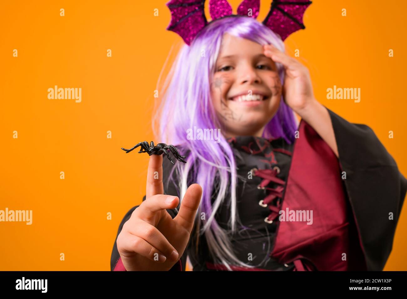 Sorridente bambina in costume da strega . Persona che posa su uno sfondo giallo nello studio. Spazio di copia. Foto di alta qualità. Banner Foto Stock