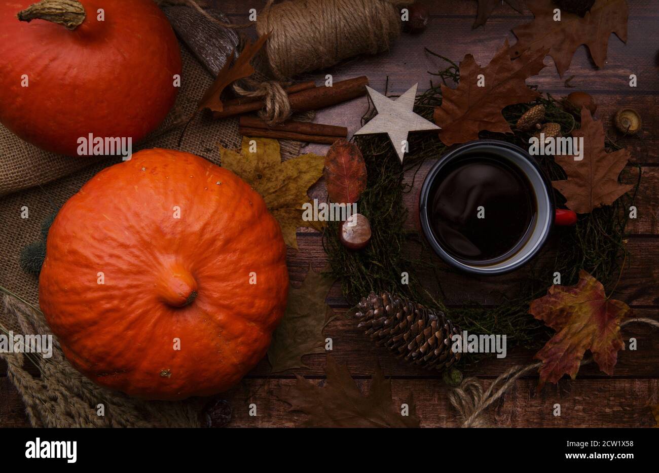 tazza con caffè su un tavolo di legno accanto alle zucche e una corona d'autunno Foto Stock