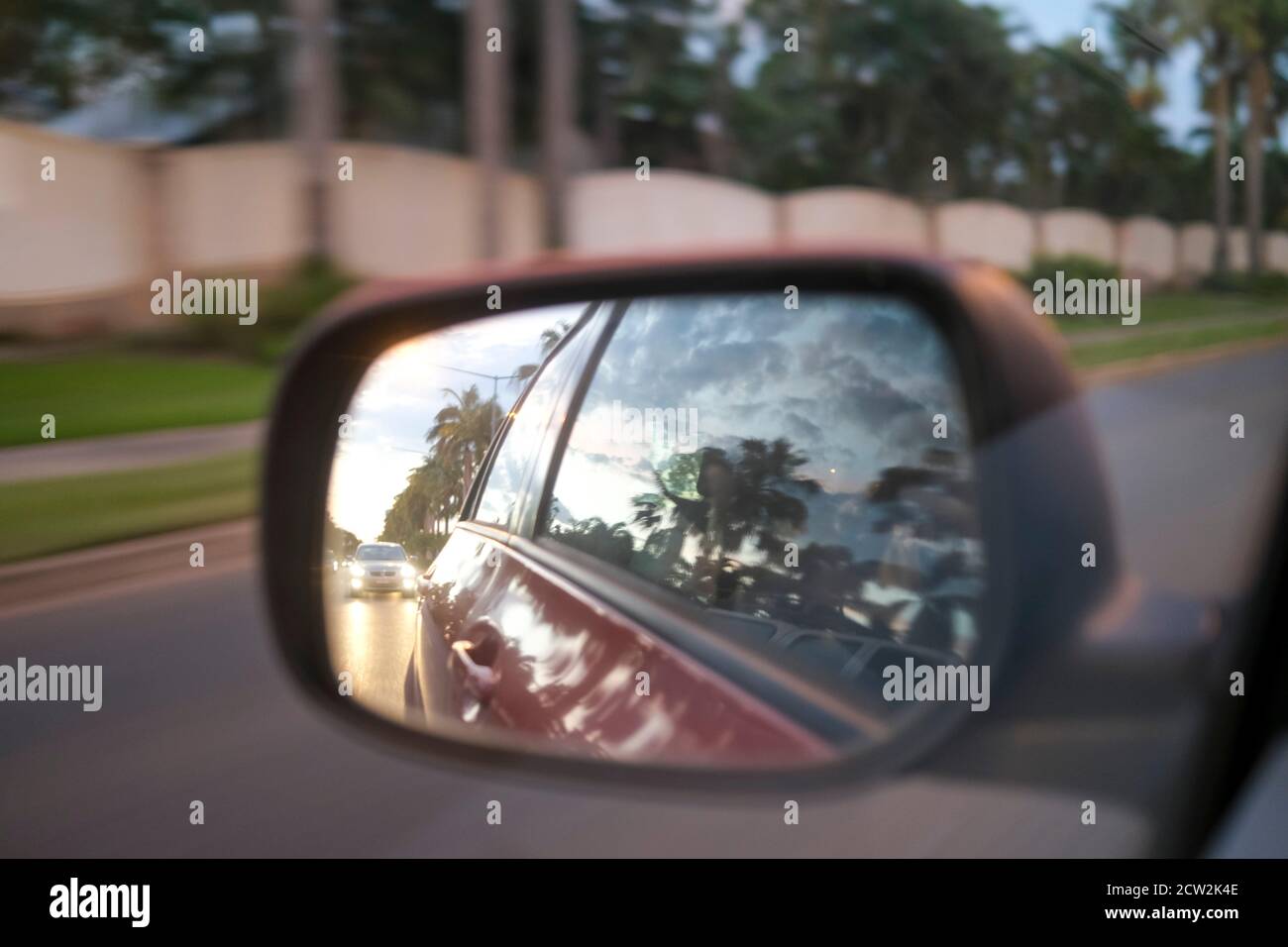 Specchio retrovisore laterale da un'auto in movimento con sfocatura del movimento di sera Foto Stock