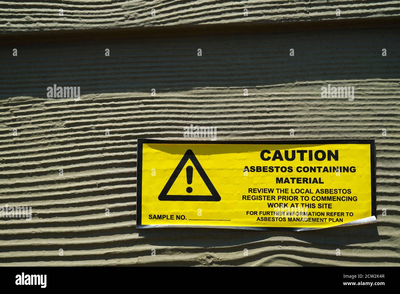Attenzione adesivo in amianto sulla parete esterna di una costruzione Foto Stock