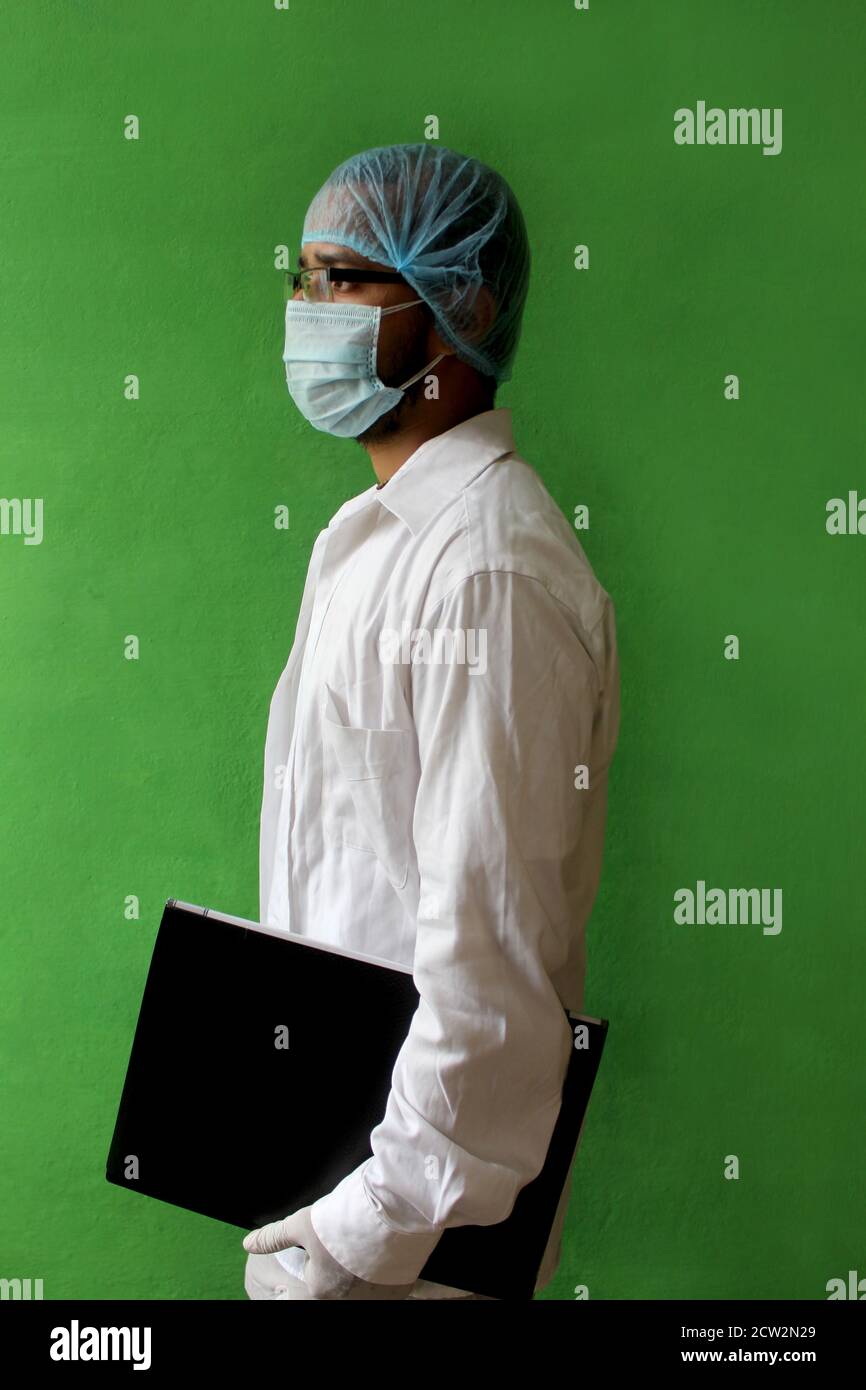 giovane medico in uniforme medica con una maschera protettiva per il viso e un guanto che tiene la cartella paziente in covid-19, corona virus. Foto Stock