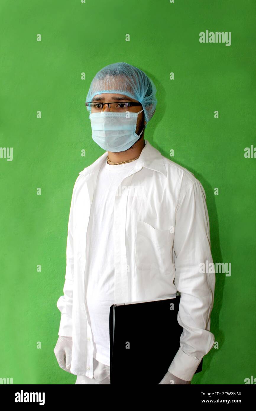 giovane medico in uniforme medica con una maschera protettiva per il viso e un guanto che tiene la cartella paziente in covid-19, corona virus. Foto Stock