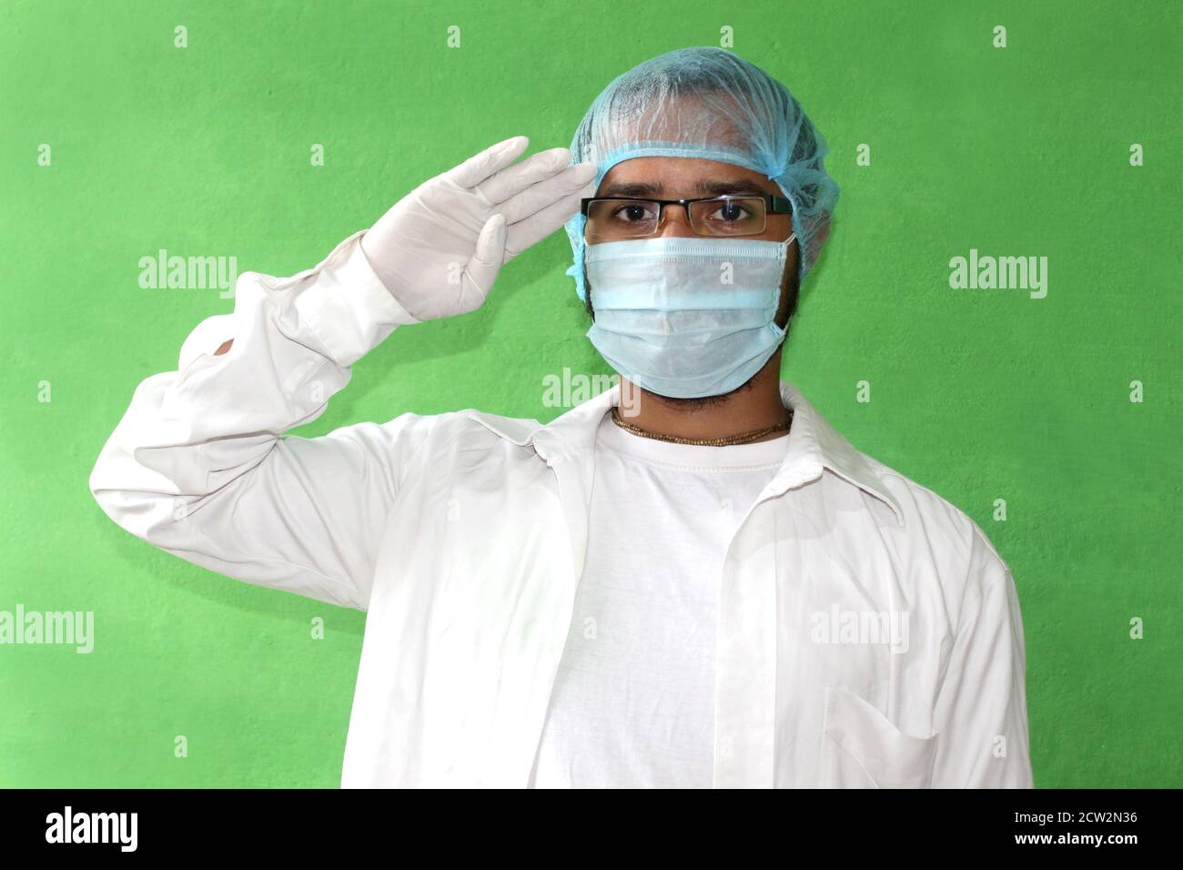Un giovane medico in uniforme medica con una maschera protettiva per il viso e guanti per le mani in saluta durante covid-19, corona virus. Foto Stock