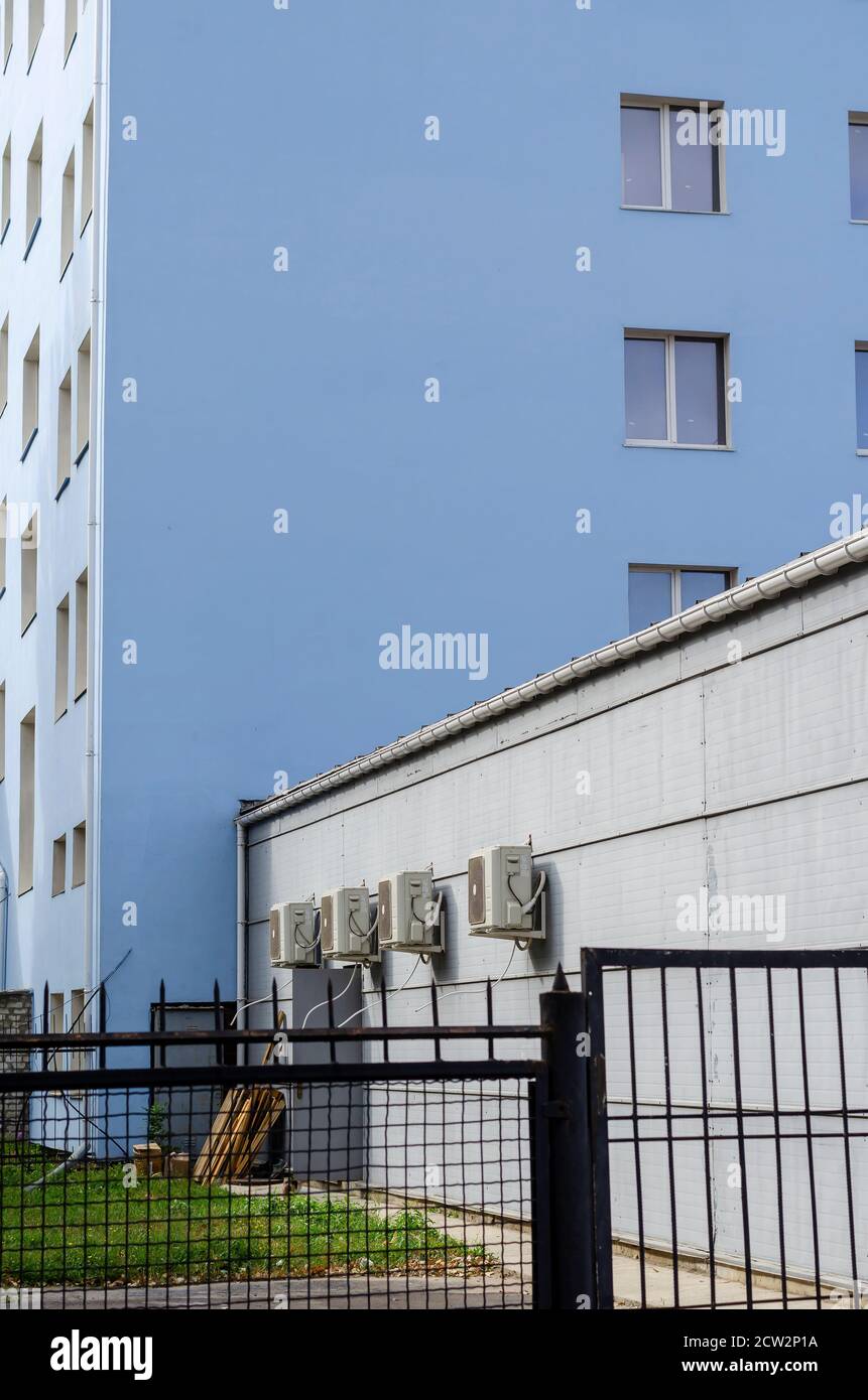 Parete del cortile con unità di climatizzazione. Area protetta dietro una recinzione metallica nera. Vita in città. Senza nessuno Foto Stock