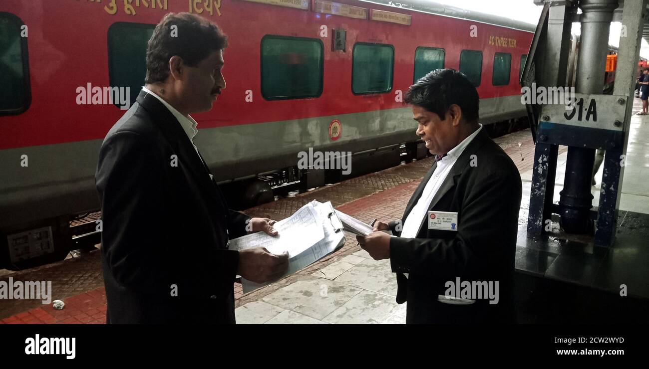 DISTRETTO KATNI, INDIA - 07 AGOSTO 2019: Due collezionisti di biglietti indiani che ispezionano i passeggeri in lista d'attesa davanti al treno alla piattaforma. Foto Stock DISTRETTO KATNI, INDIA - 07 AGOSTO 2019: Due collezionisti di biglietti indiani che ispezionano i passeggeri in lista d'attesa davanti al treno alla piattaforma. Foto Stock