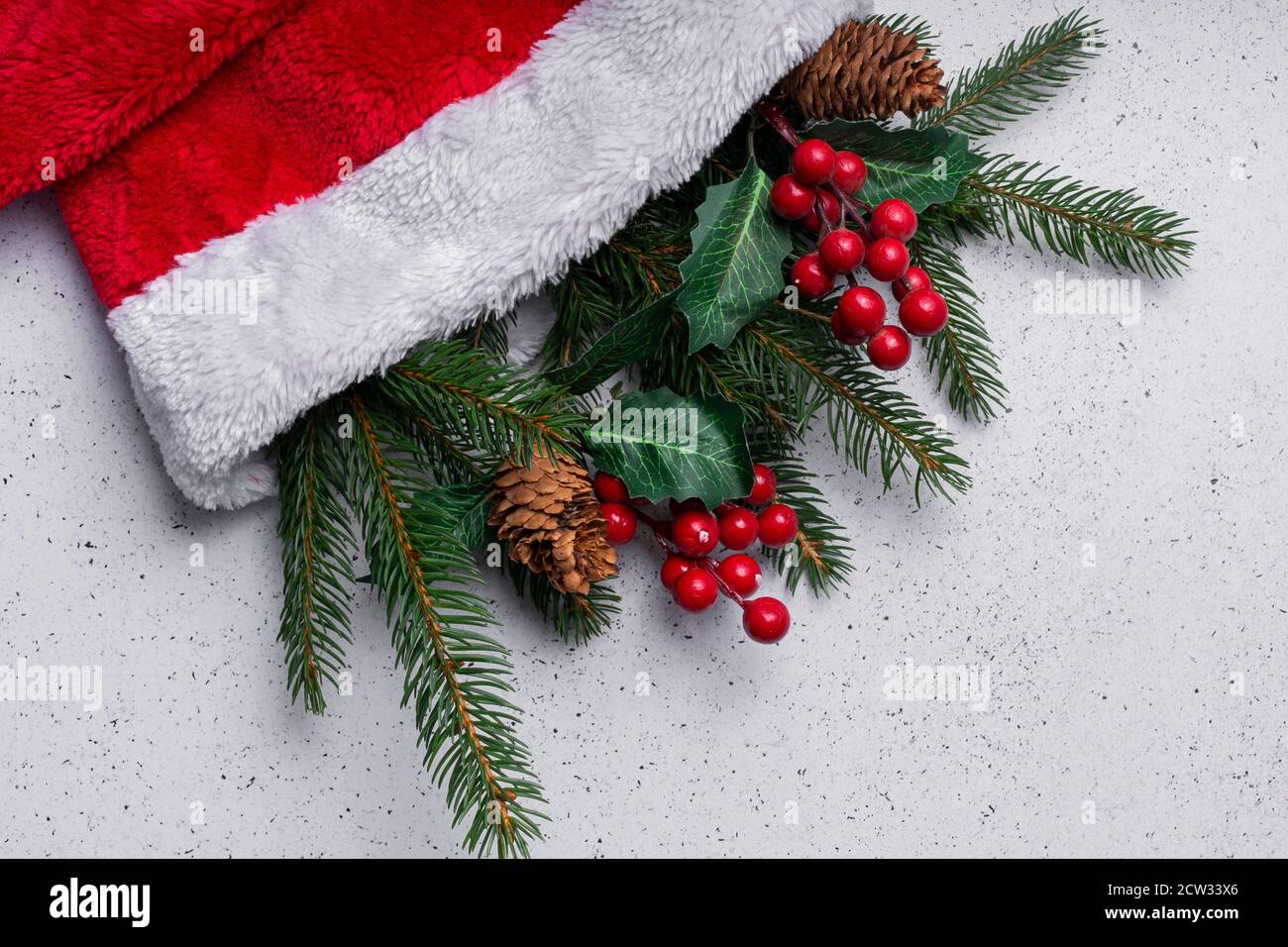 messa a fuoco selettiva. Disposizione della luce di Natale, rami dell'albero e decorazioni in un cappello rosso morbido di Natale Foto Stock