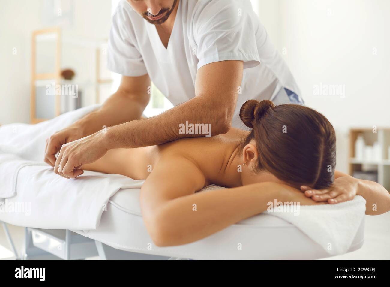 Massaggiatore professionista che fa massaggio del corpo per la giovane  donna sdraiata sopra tavolo massaggiante Foto stock - Alamy