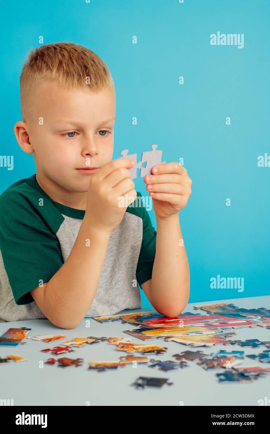 ritratto di un ragazzo che collega puzzle.on uno sfondo blu Foto Stock