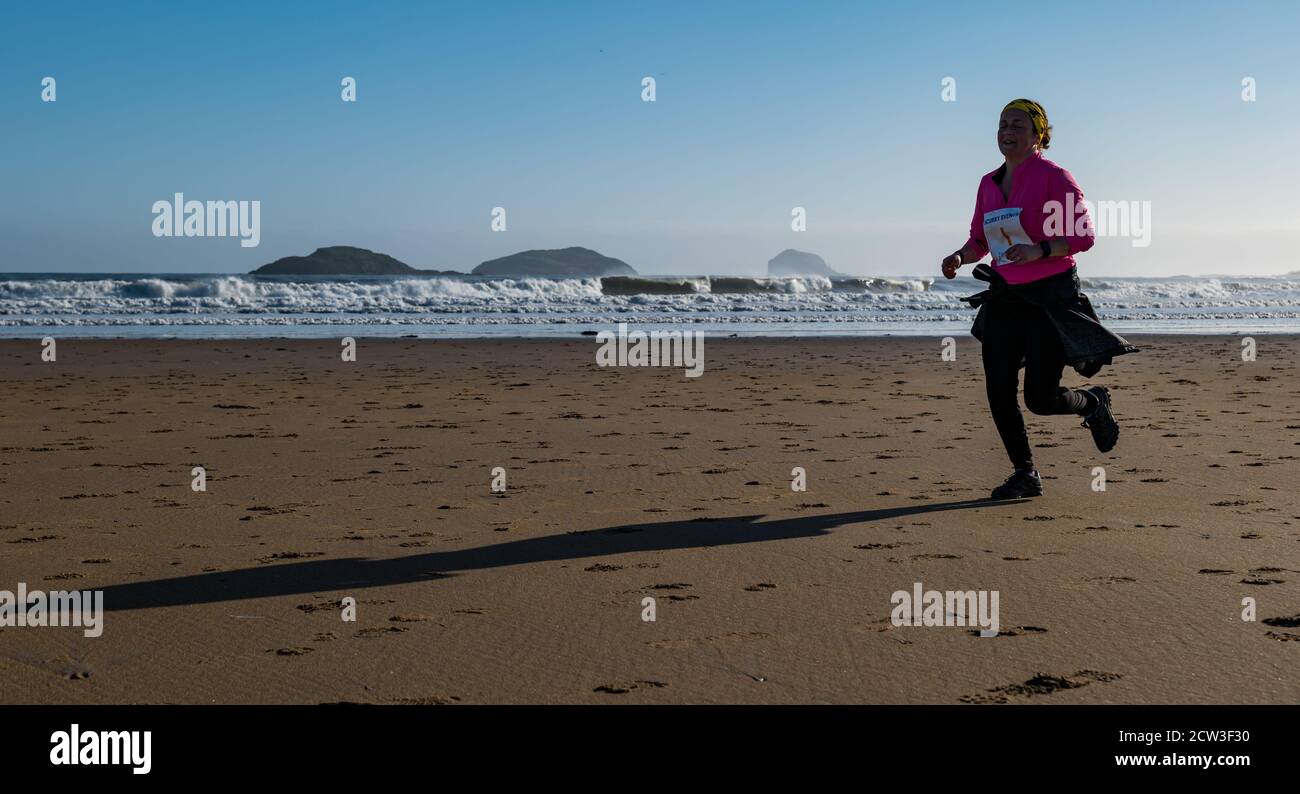 East Lothian, Scozia, Regno Unito, 27 settembre 2020. Scurry running event: I runner prendono parte a un divertente evento di corsa dalla spiaggia di Yellowcraig a North Berwick e ritornano in una bella e soleggiata mattinata d'autunno. Una corridore femminile sulla spiaggia di Broadsands con le isole Firth of Forth sullo sfondo Foto Stock
