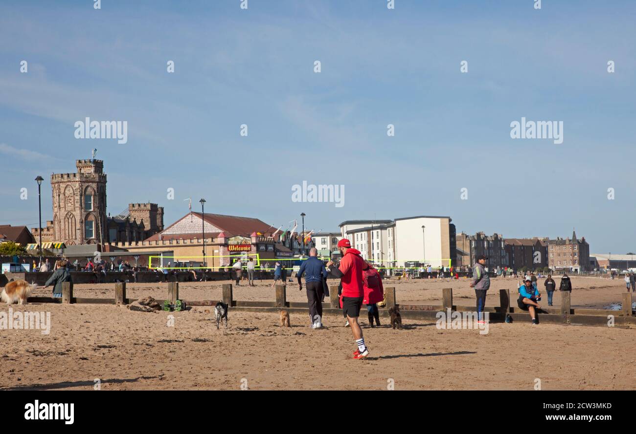 Portobello, Edimburgo, Scozia, Regno Unito. 27 settembre 2020. Dopo recenti consigli del governo che esortano il pubblico a rimanere attivo per evitare problemi di salute mentale e altri problemi di salute, le persone raffigurate oggi sul mare soleggiato sembrano prestare attenzione, a parte un gruppo di giovani che sembrano non essere consapevoli della necessità di distanziare socialmente in piccoli gruppi mentre si siedono sulla sabbia in un gruppo di quasi una dozzina. Il tempo autunnale con una temperatura di 4 gradi dopo una notte fredda e la mattina non ha tenuto la gente dentro poichè godono l'atmosfera occupata. Foto Stock